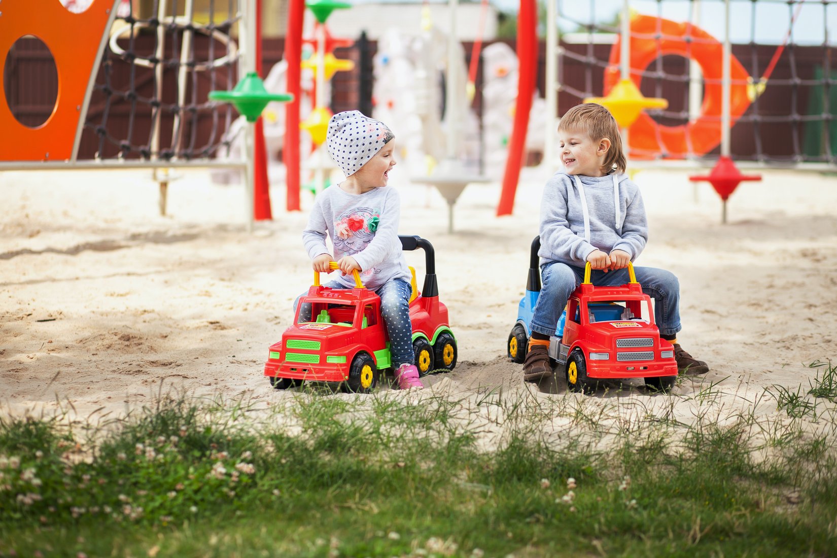 Deti jazdiace na červených hračkárskych autách na ihrisku